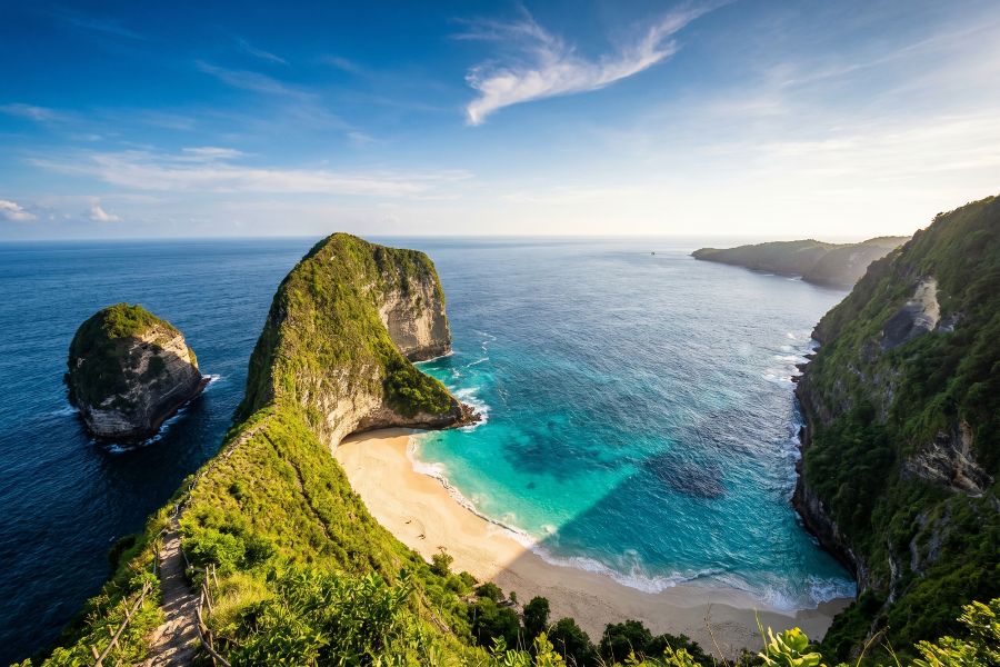 Dramatic aerial view of Kelingking Beach on Nusa Penida, with its iconic T-Rex shaped limestone cliff dropping 200 metres to a hidden white sand beach and vivid turquoise water below