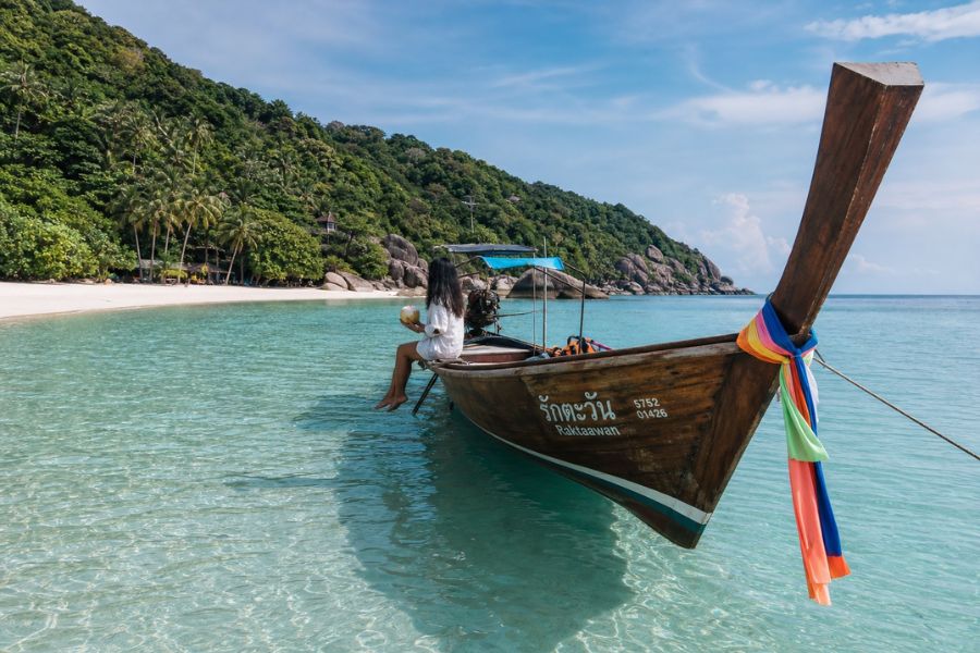 A traditional Thai longtail boat floating on transparent turquoise water in Koh Tao, a top snorkeling tour in Thailand.