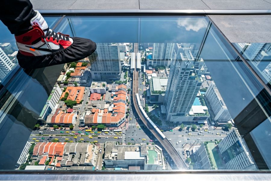 A first-person view looking through the glass floor of the Mahanakhon SkyWalk down to the Sathon district in Bangkok, one of the top 15 tours in Thailand.